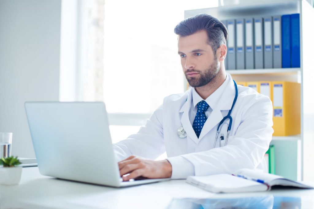 Male doctor using a laptop at his desk