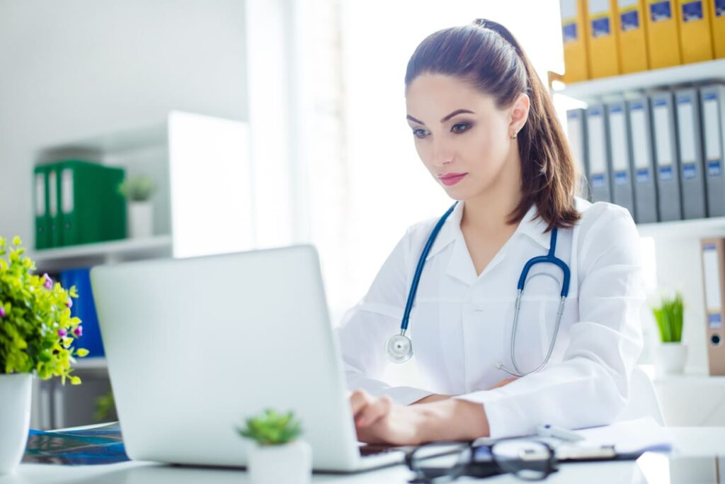 Female doctor using a laptop to update Centro Clinical Documentation Improvement to improve the patient records